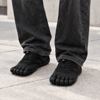 All Black five-toe shoes worn as a left and right pair with relaxed charcoal denim